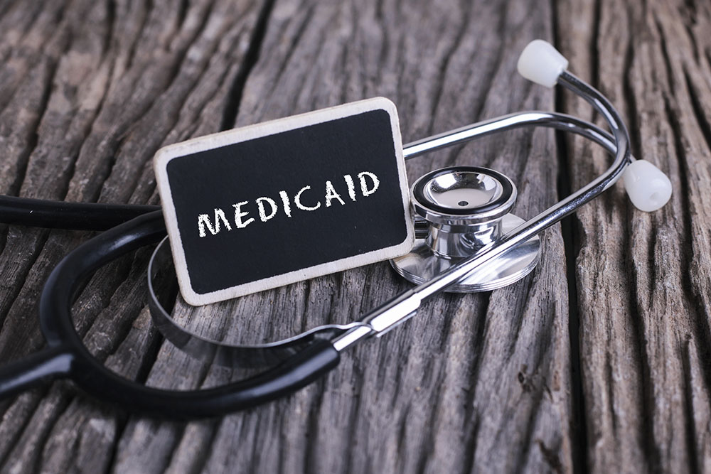 Using Medicaid to pay for an ill spouse; blackboard with word MEDICAID and stethoscope